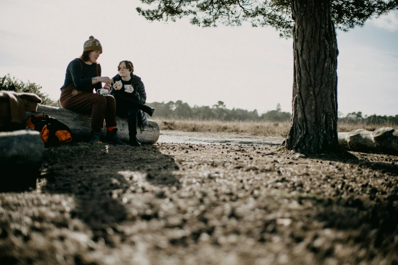 two people sitting next to each other in a field