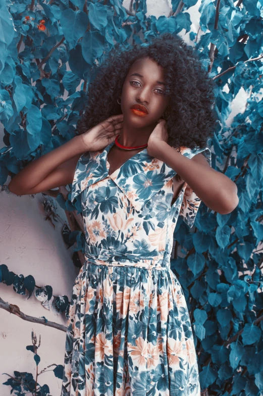 a young woman is posing in front of a vine