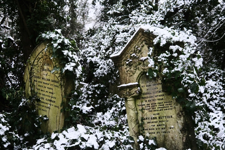 three stone heads of graves with snow on them