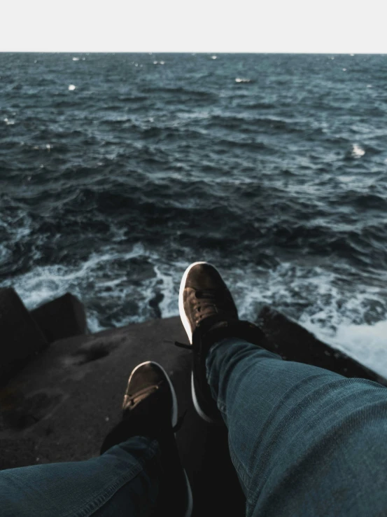 a person is standing next to the ocean with their feet on the edge