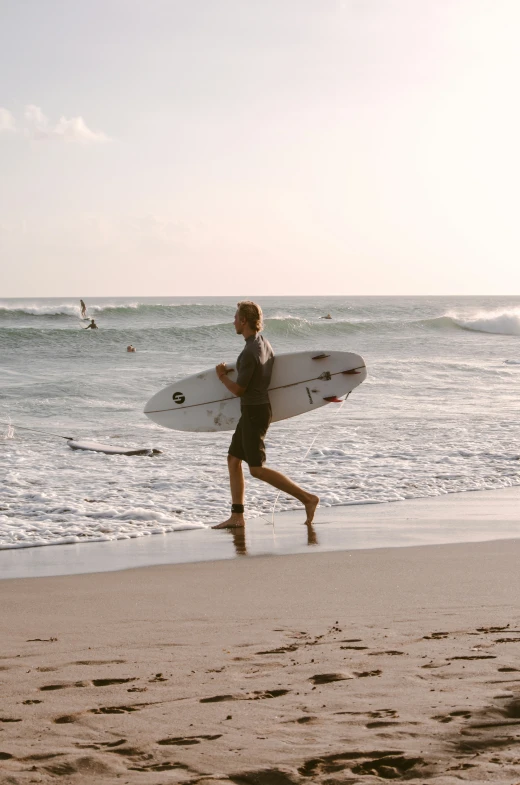 a surfer running on the beach with his board in hand