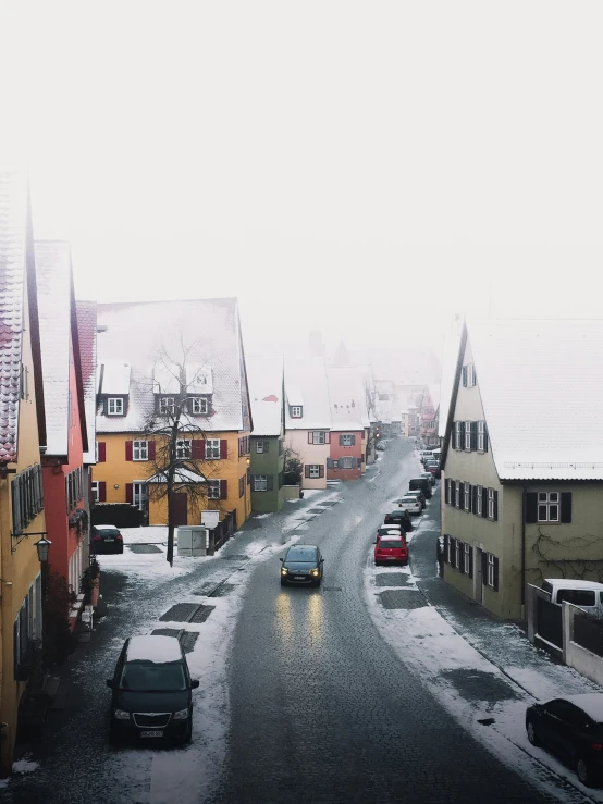 some houses are along a snowy road and two cars