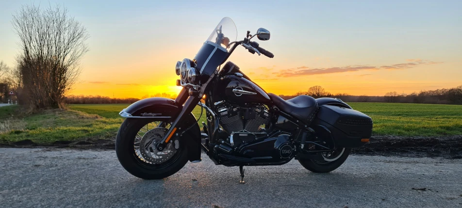 an all black motorcycle with the sun going down in the background