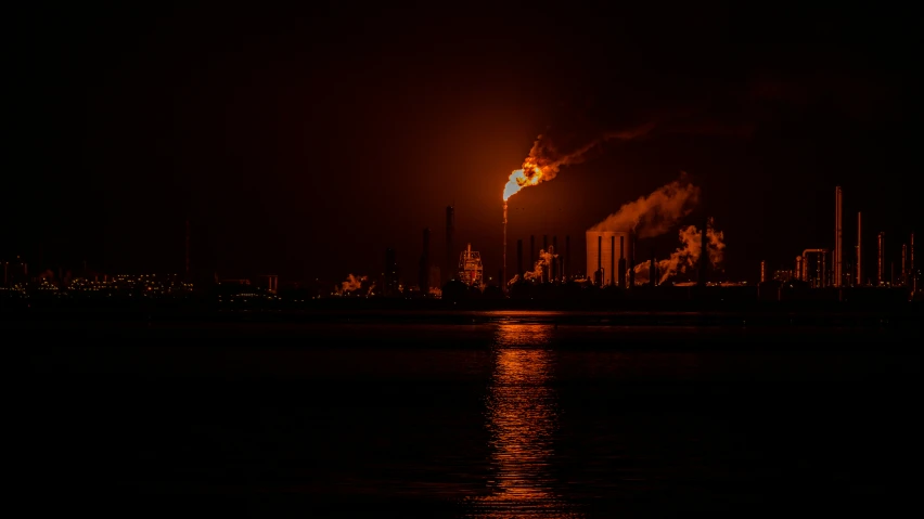 an industrial city at night time with smoke coming from the pipes