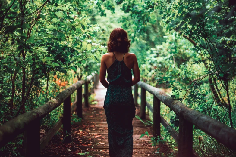 a woman in a long dress stands on a bridge