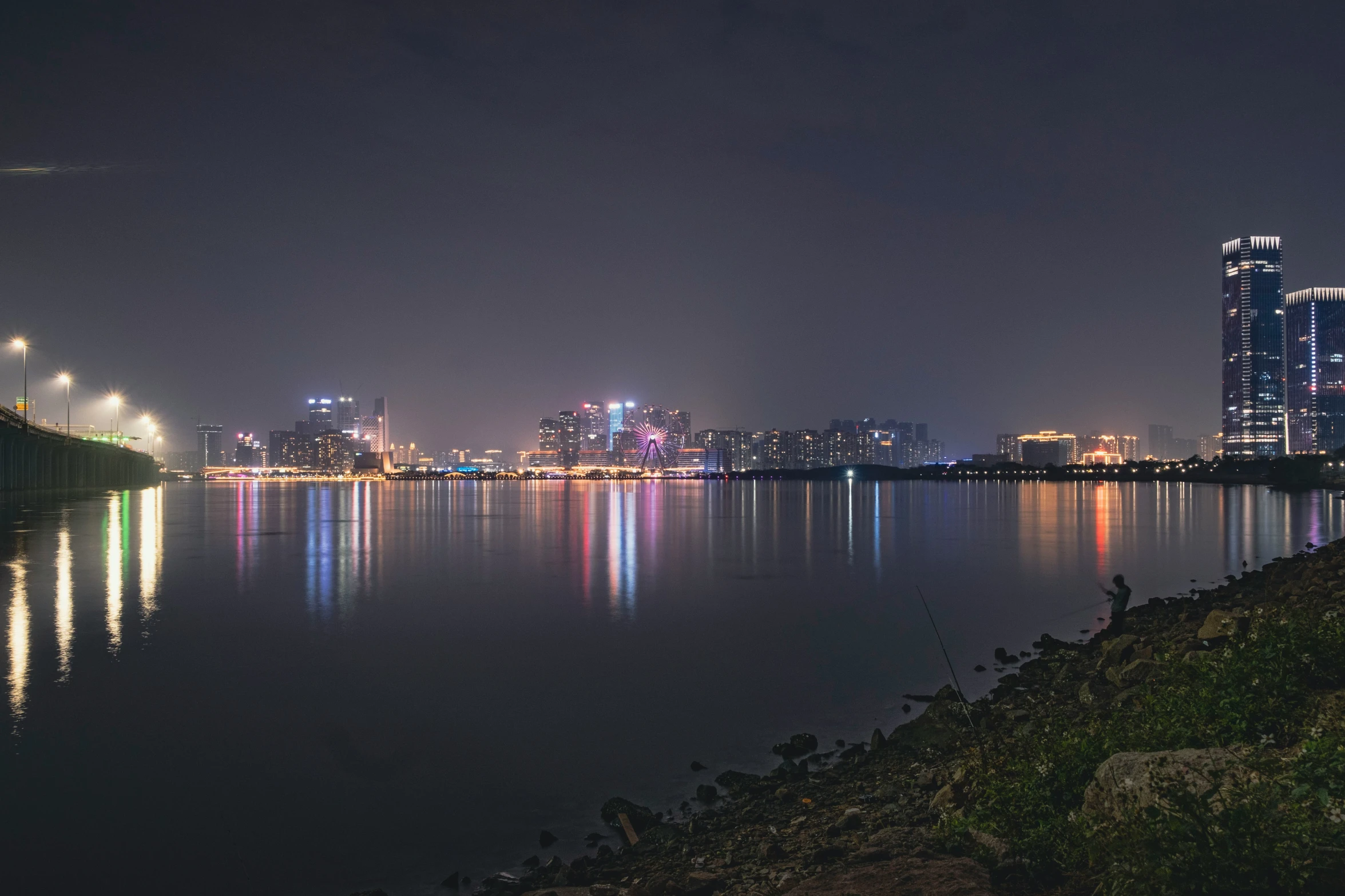 a view of a city lit up at night, with reflection in the water