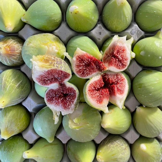 green and red fruit on grey background including figs