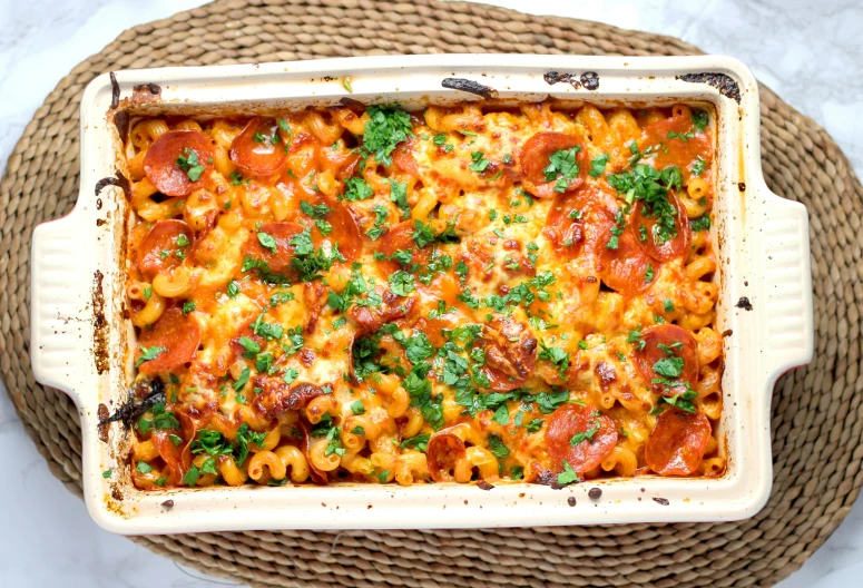 a dish of macaroni with red sauce, parsley and pepper