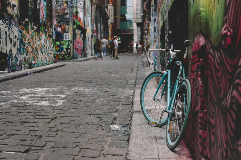 two blue bikes parked by the side of the street