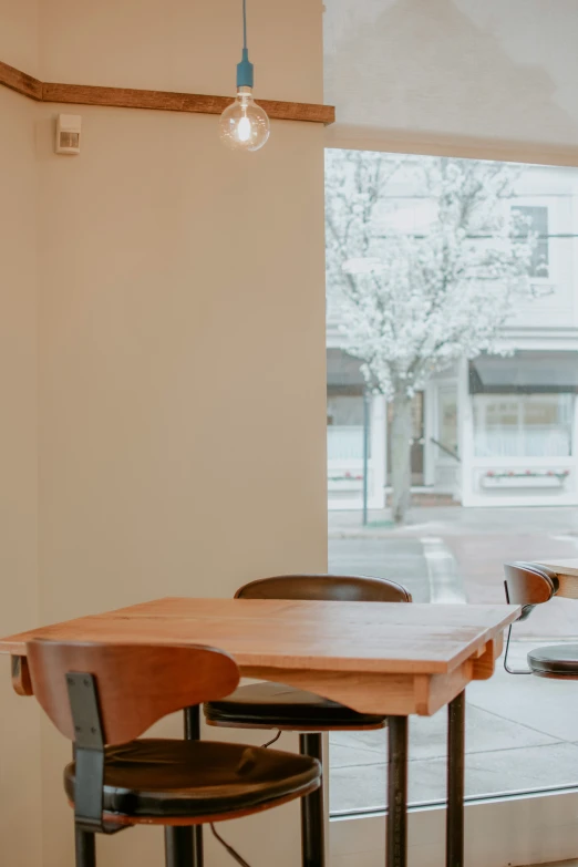 a wooden table and two black chairs near a window