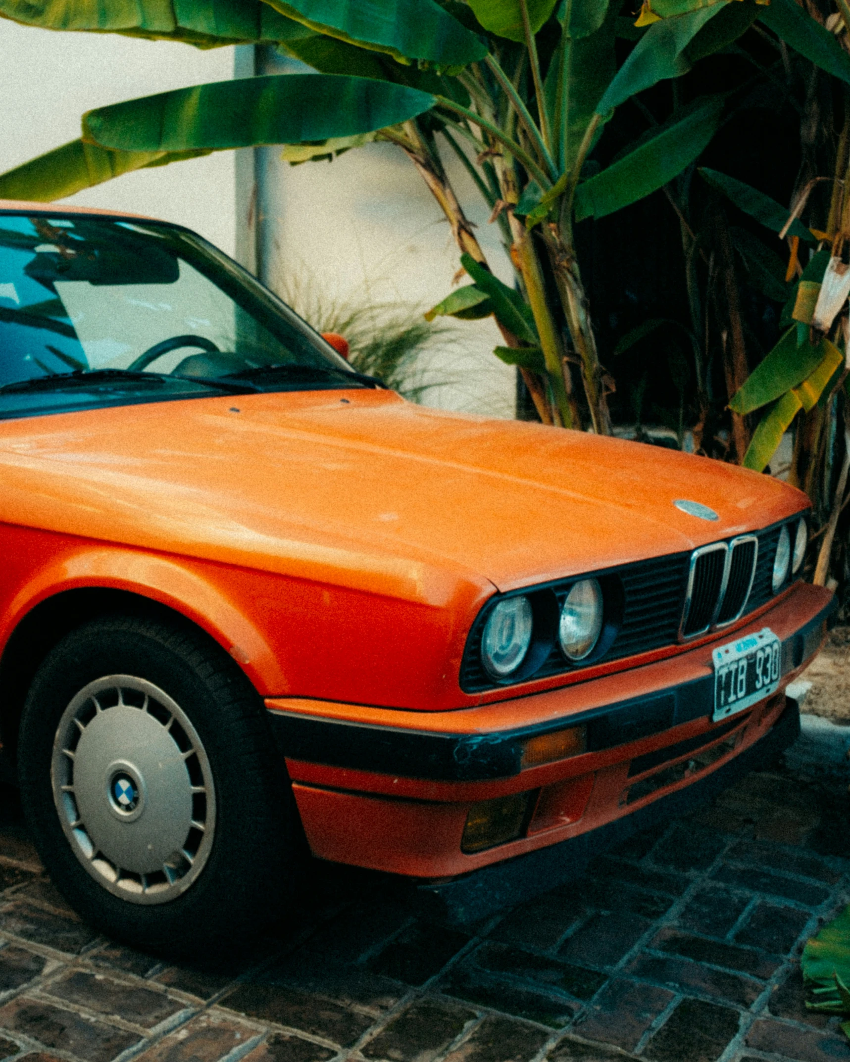 an orange car that is parked near a tree