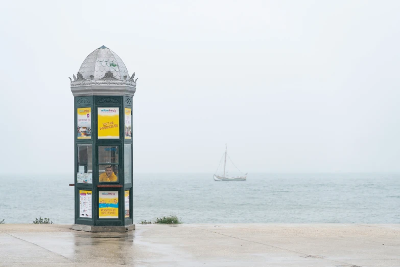 a small green kiosk next to the ocean