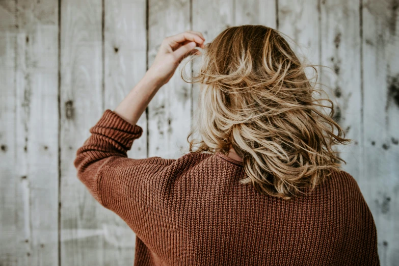 a woman is holding her hair up and looking away