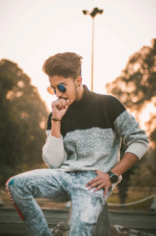 a man sitting in the park holding his nose to his ear