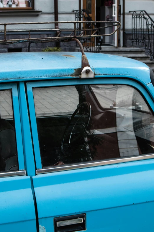 the front window of an old blue truck with a bird on top