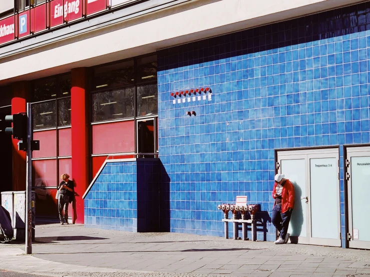 a blue building with red accents and people seated outside