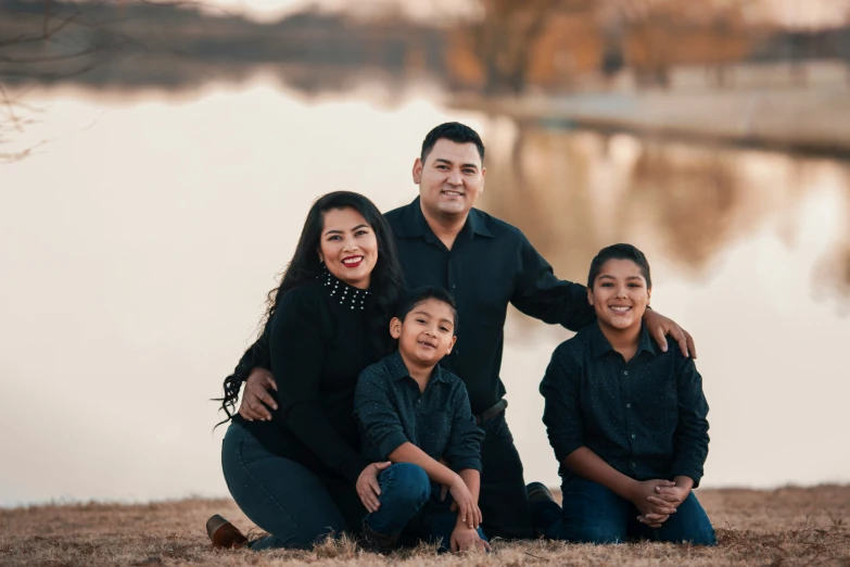 an indian family poses in front of a lake for a po