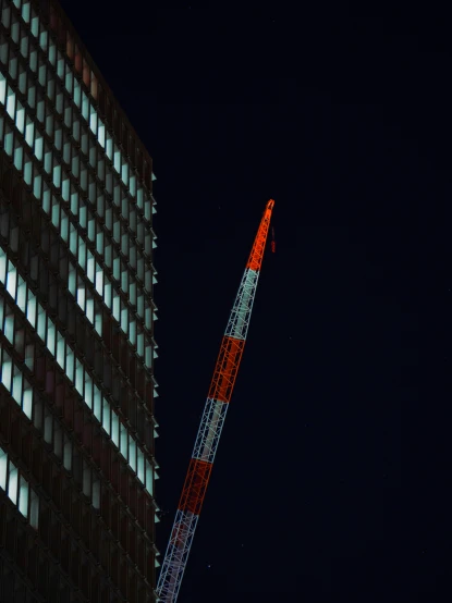 a tall tower with a crane on top of it at night