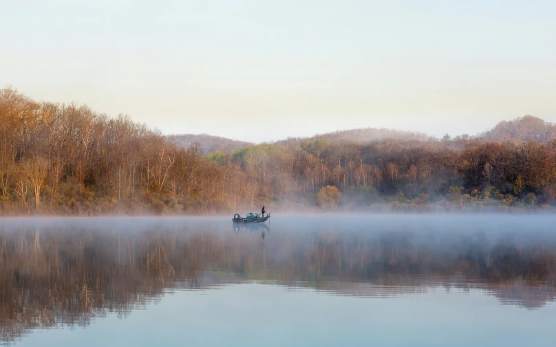 a canoeer is on a lake in the middle of a forest