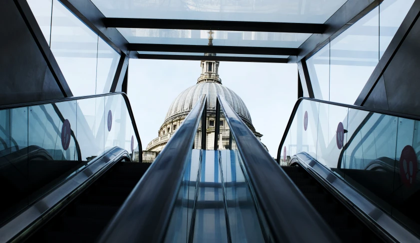 escalators leading in to a building with big ben towering over it