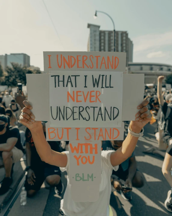 a man holds up a sign saying, i understand that i will never understand but i stand who you think