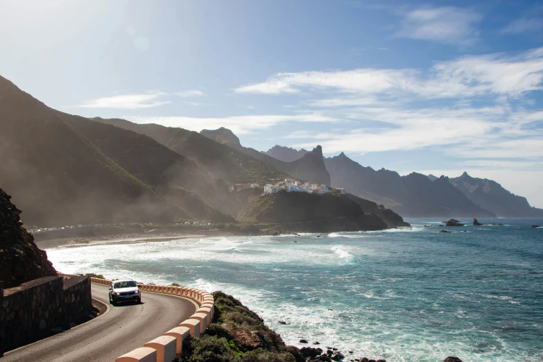 a street passing by the ocean near a hill