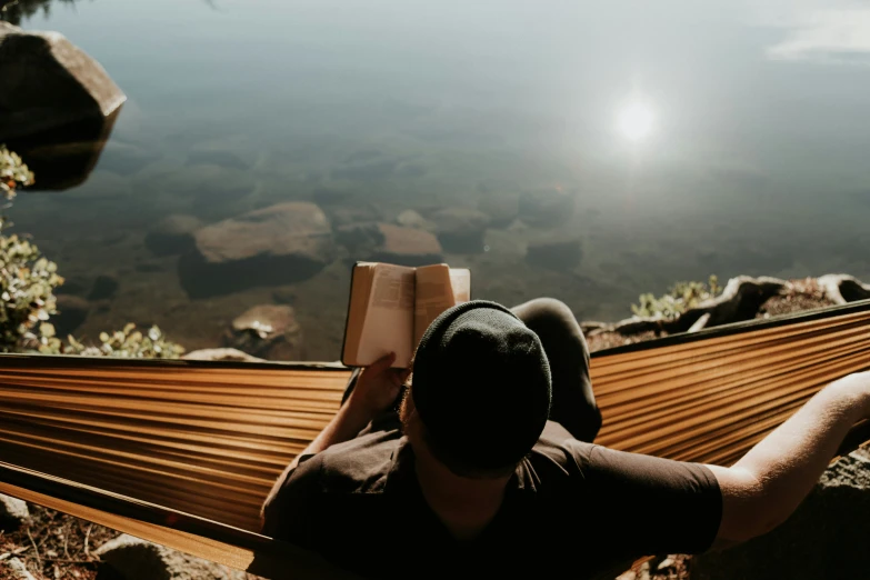 a man sitting in a hammock with an open book