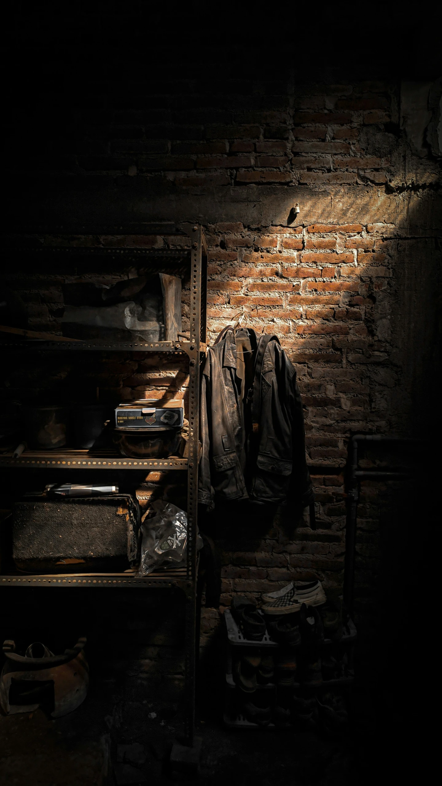 a dark room with a light shines on a clothes rack