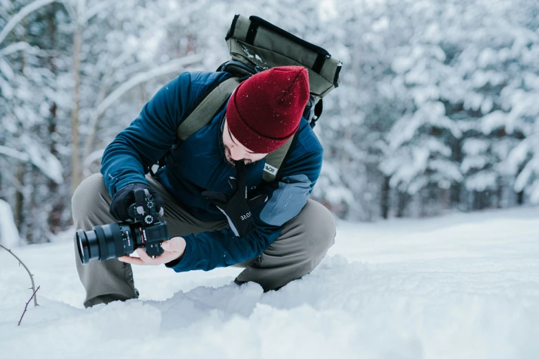 a pographer kneeling down in the snow with his camera