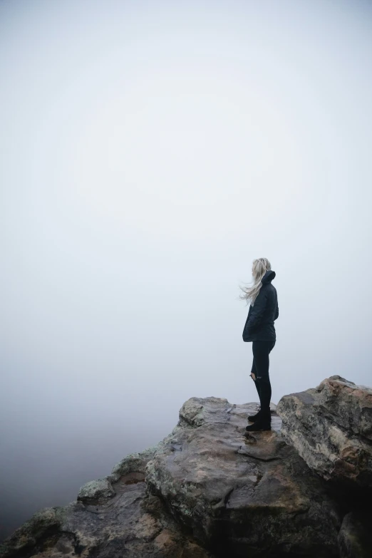 a girl on top of a cliff looking at soing