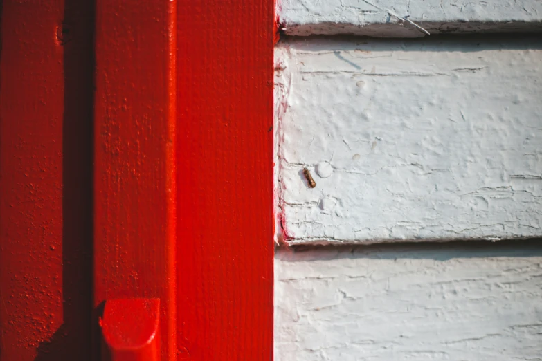 a red handle on a door next to a white painted wall