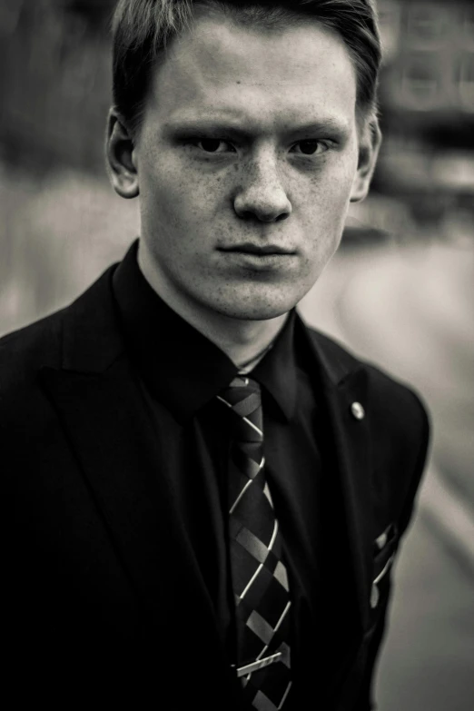a young man with a tie standing in front of a street
