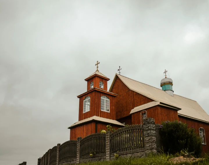 a tall red building with two steeples and a fence