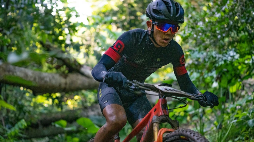 a mountain biker wearing goggles is making a turn on a trail in the woods