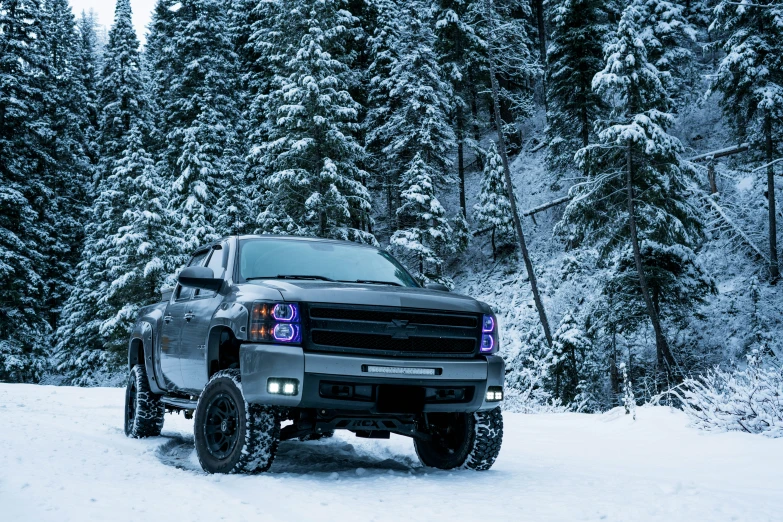 a silver truck driving on top of a snow covered road