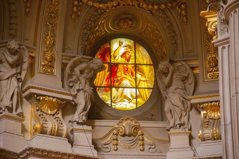 a window showing an image of jesus with his arms raised and other statues below