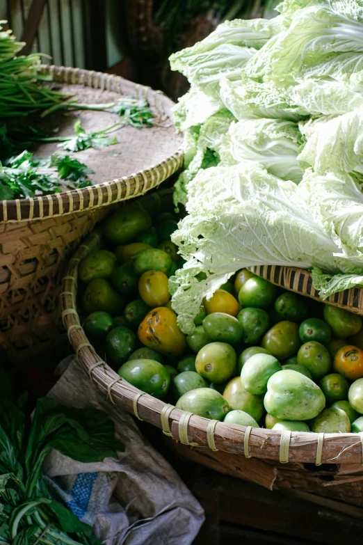 several baskets of vegetables are lined up with one large cabbage