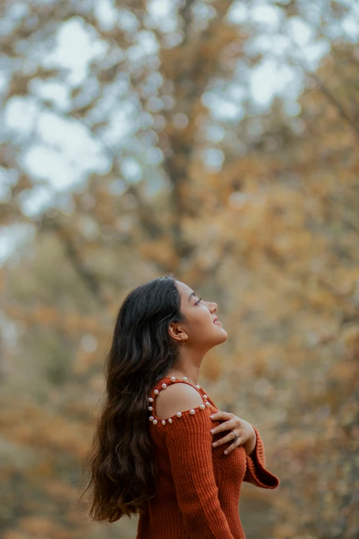 the woman in the sweater is looking up into the air