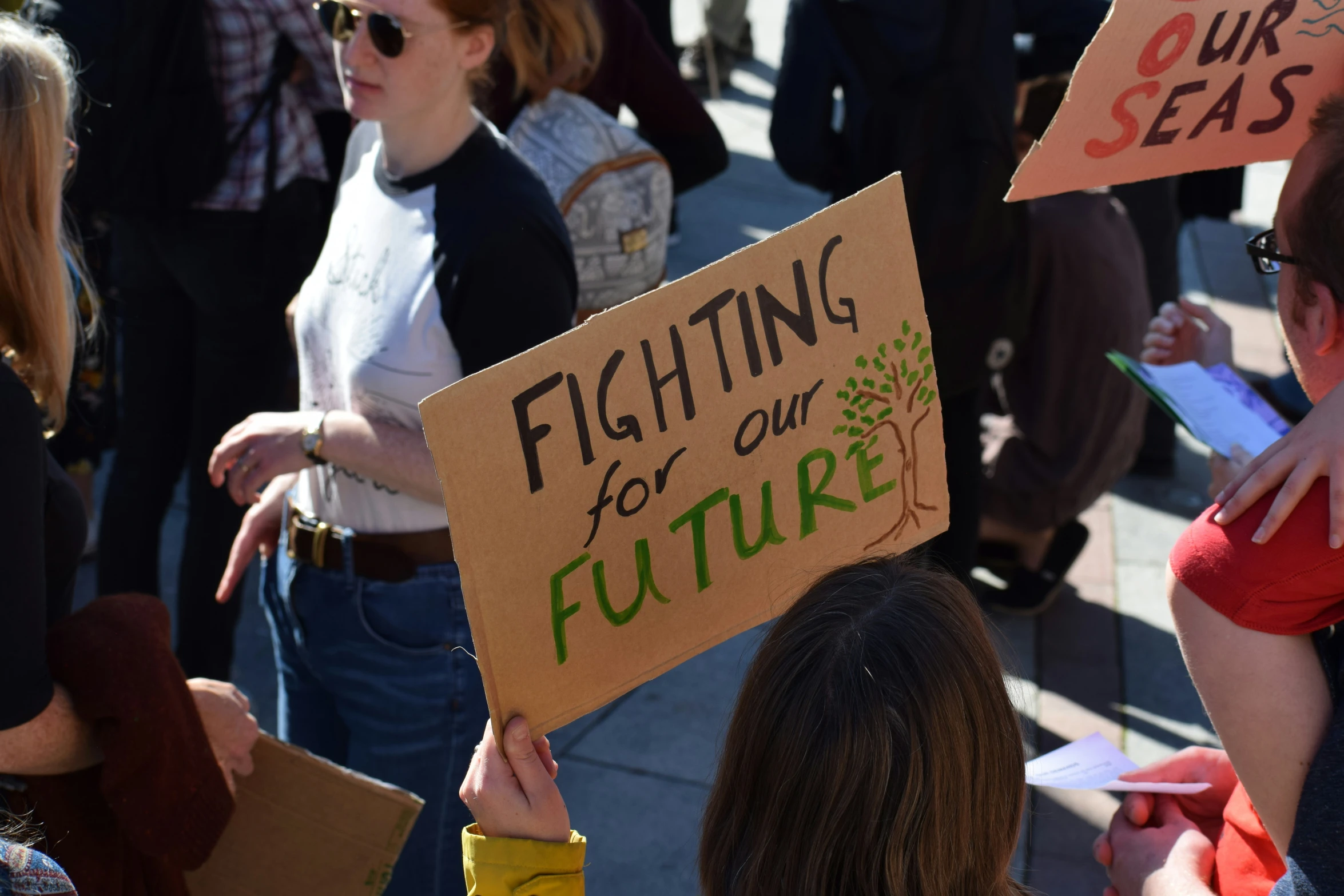 people in line with signs on them protesting for the future