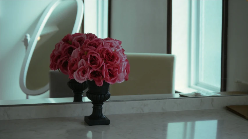 there is a vase with flowers sitting in front of a mirror