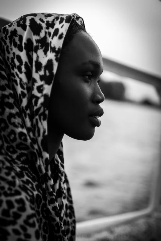 a woman in a hoodie standing next to a fence