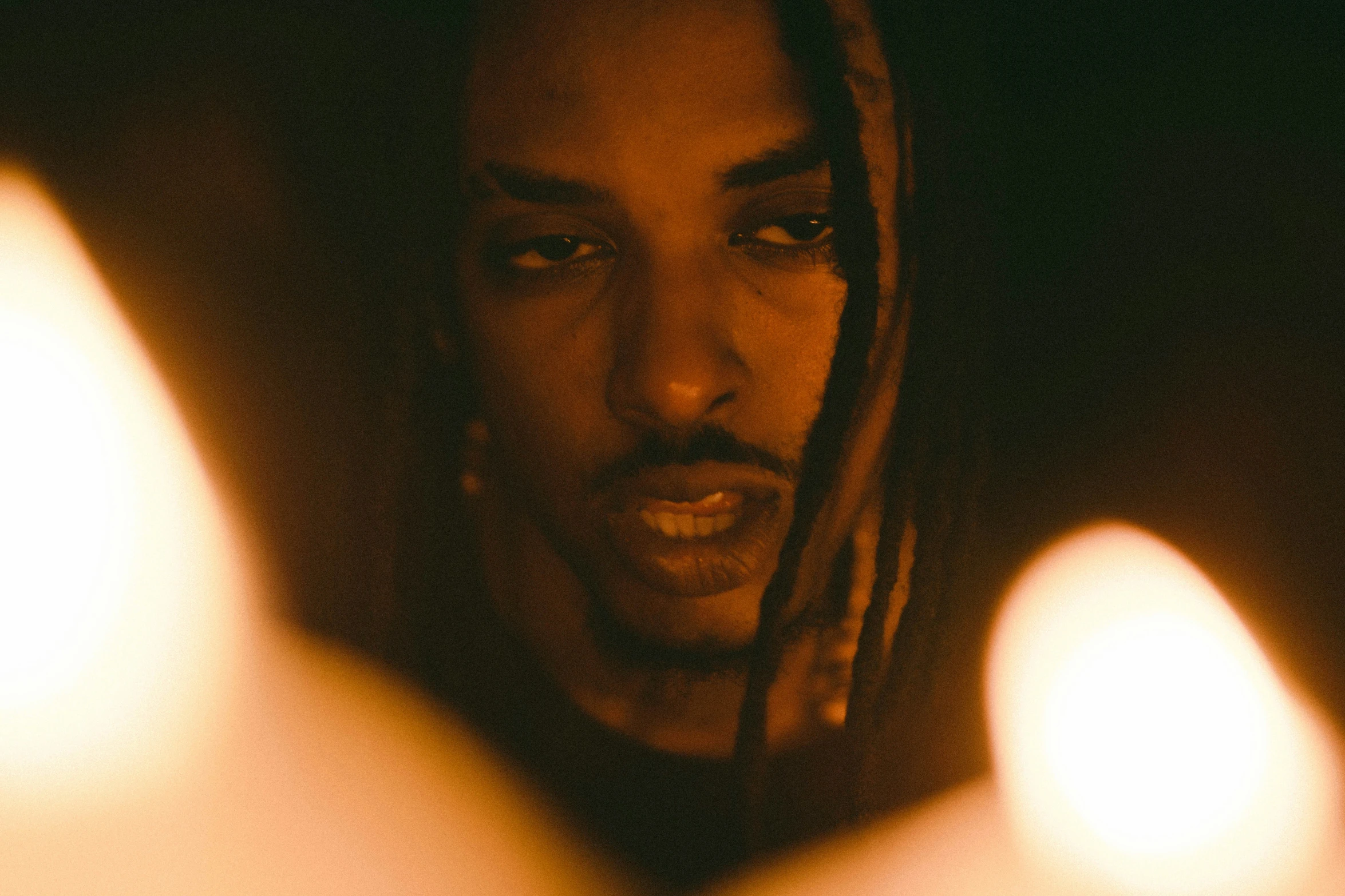 a man staring at candles while wearing a sweater