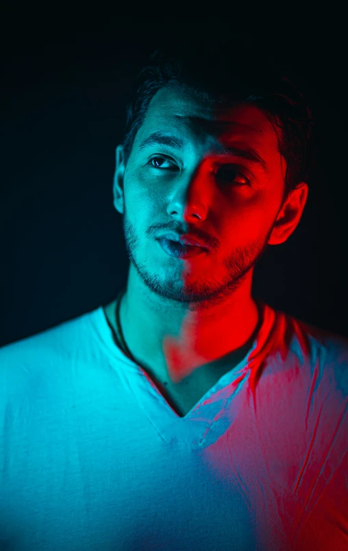 a man in a v - neck tee in front of a dark background