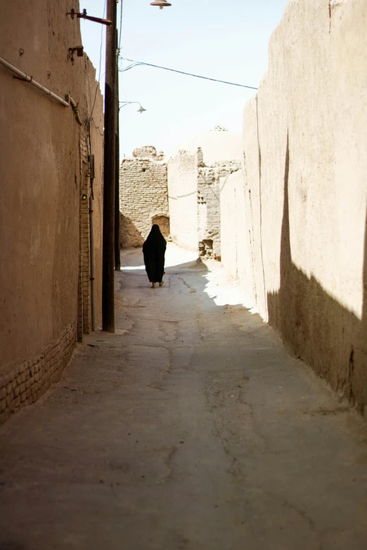 a woman walks down a narrow alley with two walls