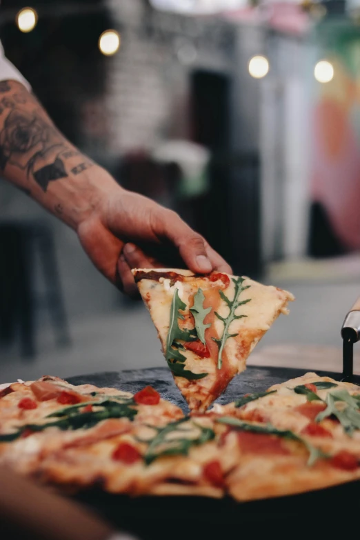 the person with tattoos is  into two slices of pizza