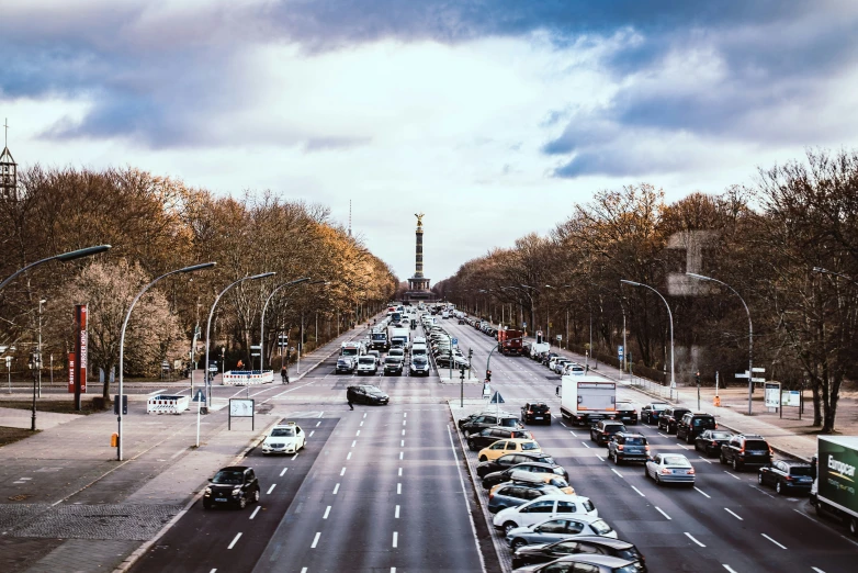 the view of several lanes in one direction and a car approaching a stop sign at an intersection in another