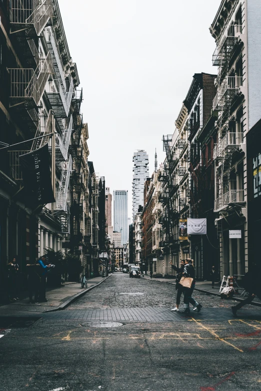 an empty street with tall buildings and people walking on the sidewalk