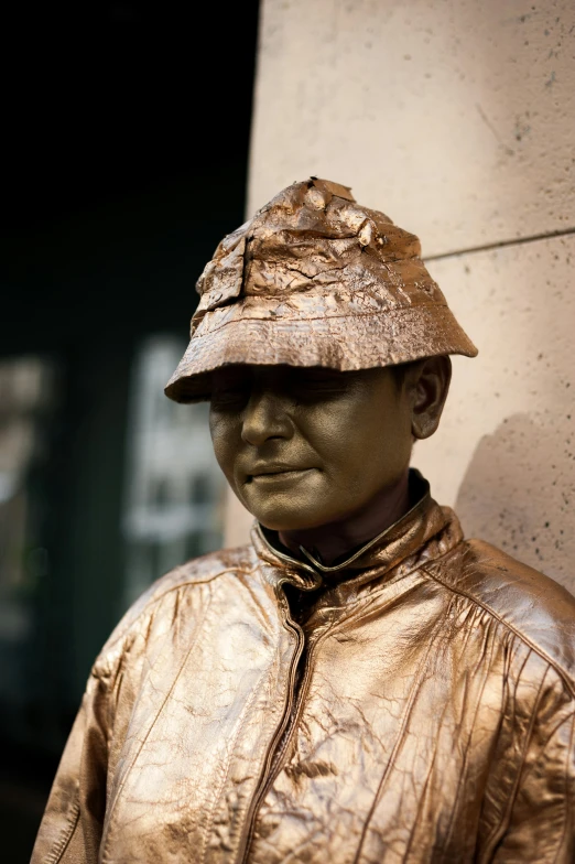 bronze statue of a man wearing a hat by a wall