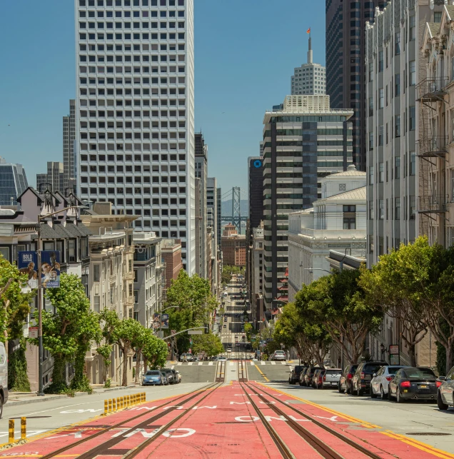 a long street with buildings and cars passing on the other side