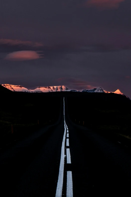 a long empty road with mountains in the background